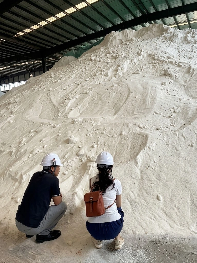 Two team members inspecting white bulk cargo inside a warehouse