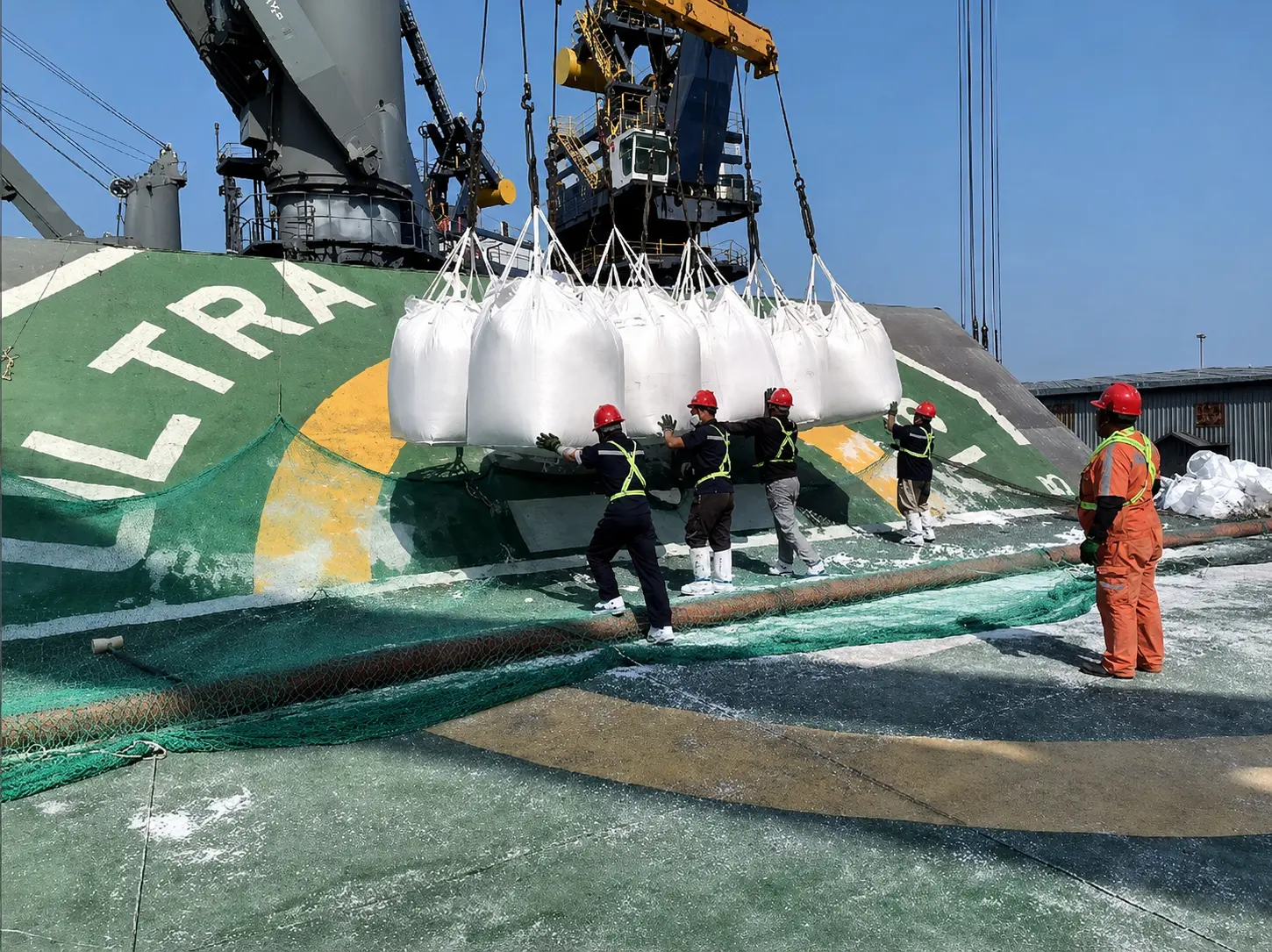 Bulk cargo bags being handled by workers on a vessel deck